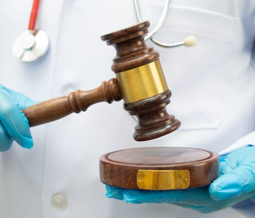 Asian doctor holding court hammer for and crime law justice, forensic medicine.