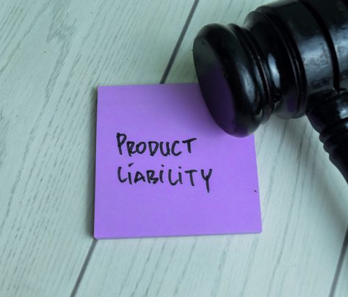 Concept of Product Liability write on sticky notes with gavel isolated on Wooden Table.